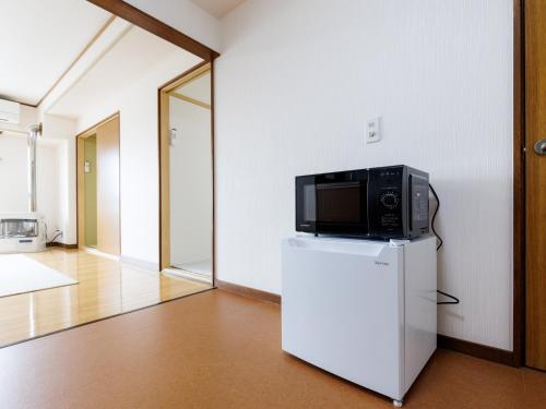 a microwave on top of a refrigerator in a room at Tabist JKNツインホテル in Asahikawa