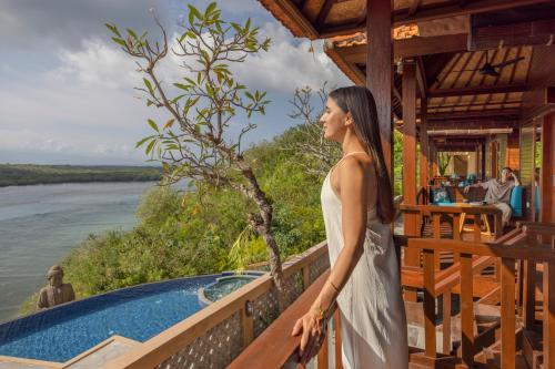 a woman in a white dress standing next to a pool at Pramana Nusa Ceningan in Nusa Lembongan