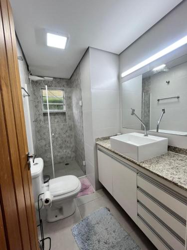 a bathroom with a white sink and a toilet at Maresias - Flat confortável in Maresias