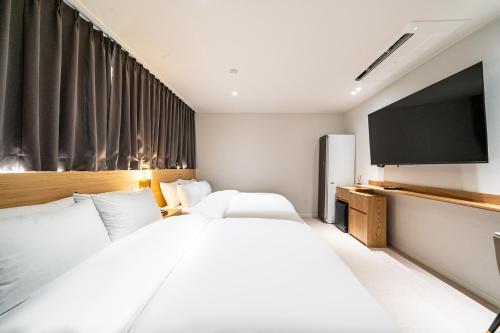 a hotel room with two beds and a flat screen tv at Brown Dot Hotel Hot Spring Yuseong in Daejeon