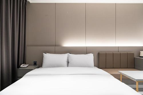 a bedroom with a large bed with white sheets at Brown Dot Hotel Hot Spring Yuseong in Daejeon