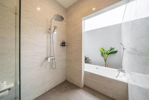 a bathroom with a shower and a tub and a sink at Modern 5BR Luxury Villa with Pool & Rooftop - 100m from Sanur Beach in Sanur