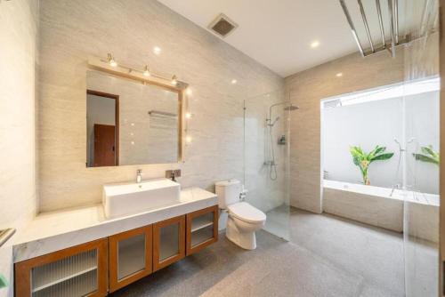 a bathroom with a sink and a toilet and a mirror at Modern 5BR Luxury Villa with Pool & Rooftop - 100m from Sanur Beach in Sanur