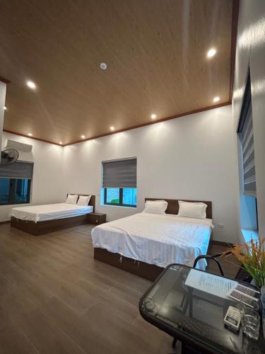 a bedroom with two beds and a desk with a glass table at BamBoo Villa Homestay in Ninh Binh