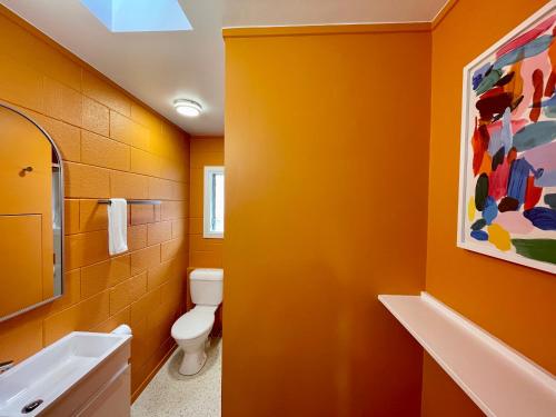 an orange bathroom with a toilet and a sink at Mount Eden Motel in Auckland