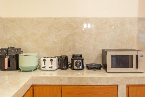 a kitchen counter with a microwave and other appliances at Modern 5BR Luxury Villa with Pool & Rooftop - 100m from Sanur Beach in Sanur