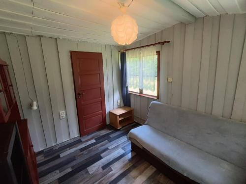a living room with a couch and a red door at Domek nad Trojanką koło Olsztyna Blisko jeziora in Wrzesina