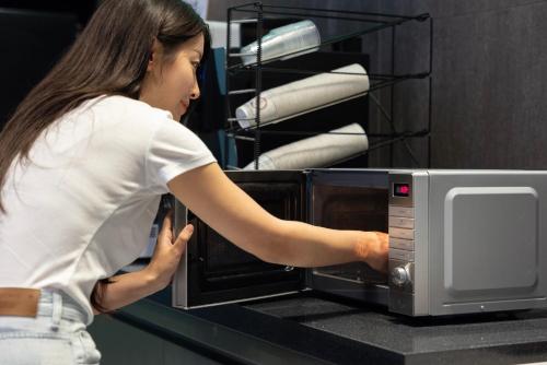 a woman is looking inside of a microwave at 호텔 데일리 안산 in Ansan