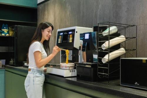 a woman standing in front of a coffee machine at 호텔 데일리 안산 in Ansan