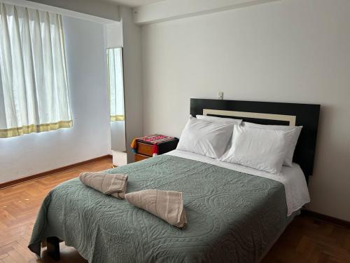 una camera da letto con un letto con una coperta verde e cuscini bianchi di Joes House- cerca al mall real plaza a Cuzco