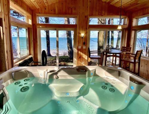 a large bath tub in a room with windows at Lakefront Pine Cottage Hot Tub & Fire Pit in Sodus