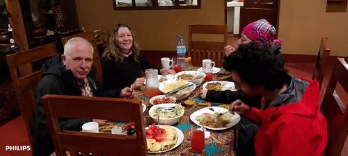 a group of people sitting around a table eating food at Kisanga Homestay in Moshi