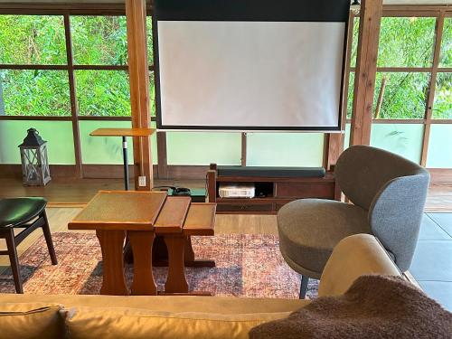 a living room with a large screen and a table and chairs at THE LAKE Kawaguchiko-kurashi in Fujikawaguchiko