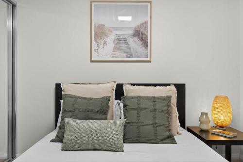 a bed with pillows and a picture on the wall at Modern 2BR Apartment in the Heart of Rockingham Close to Beach Shops & Naval Base in Rockingham