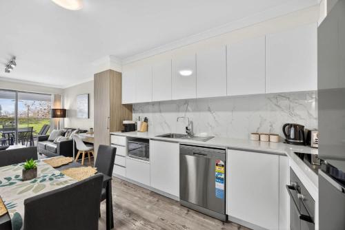 a kitchen with white cabinets and a living room at Modern 2BR Apartment in the Heart of Rockingham Close to Beach Shops & Naval Base in Rockingham