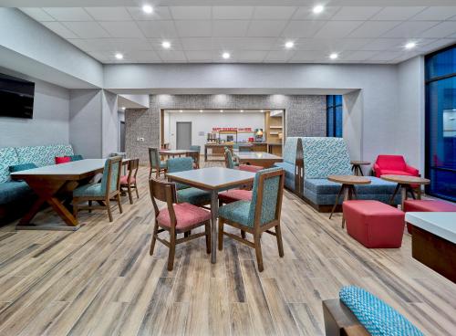 a waiting room with tables and chairs and a cafeteria at Hampton Inn & Suites Omaha Un Medical Center Area in Omaha