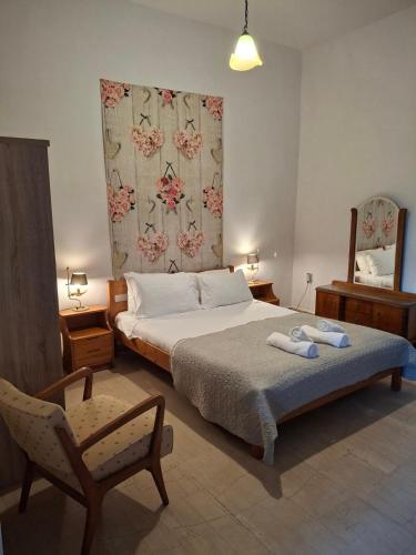 a bedroom with a bed and a chair and a mirror at THOLETO APARTMENTS in Agios Gordios