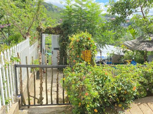a gate to a garden with lots of flowers at Cú Trên Cây Homestay in Xuan An