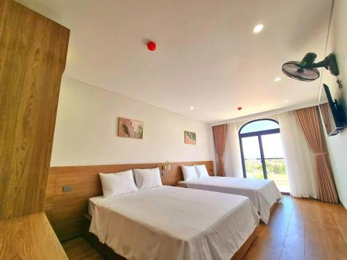 a hotel room with two beds and a window at Lisa Hotel Thiên Cầm in Cẩm Xuyên