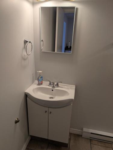 a white bathroom with a sink and a mirror at Gordie's Inn & Suites in Alert Bay