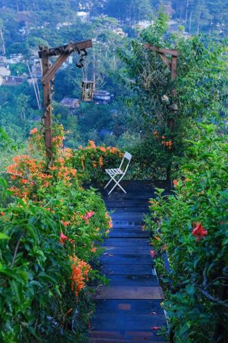 a chair sitting on a pathway in a flower garden at Cú Trên Cây Homestay in Xuan An