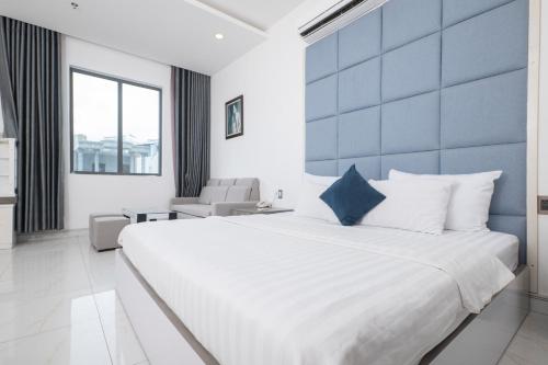 a bedroom with a large white bed with a blue wall at White Diamond Hotel in Ho Chi Minh City