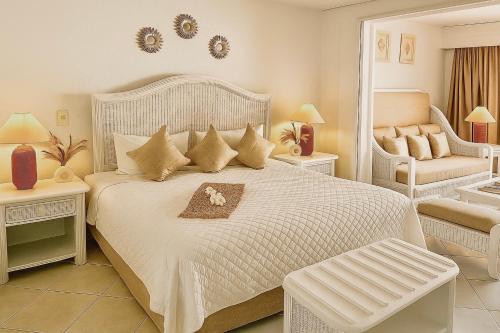 a white bedroom with a white bed and a chair at Lovely Seafront Apartment with Breathtaking Seaviews in Cupecoy