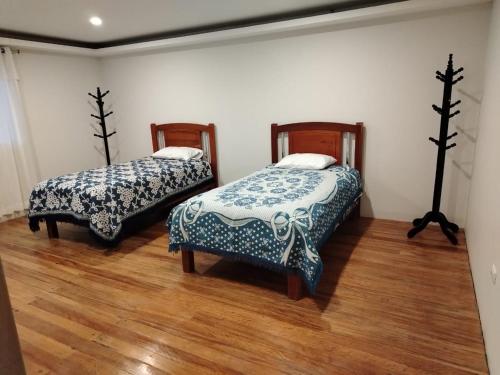two beds in a room with wooden floors at Sierra Alta House in Espinar