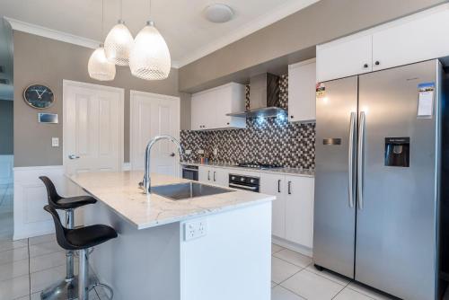 a kitchen with white cabinets and a stainless steel refrigerator at The Airport Stop Modern, 15min to Brisbane City in Brisbane