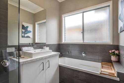 a bathroom with a sink and a tub and a window at The Airport Stop Modern, 15min to Brisbane City in Brisbane