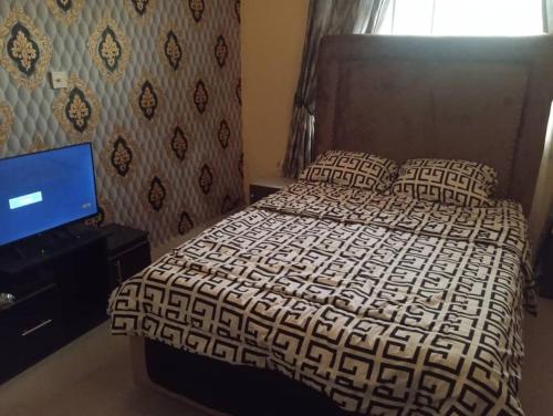 a bedroom with a bed and a flat screen tv at GA guest House in Ibadan