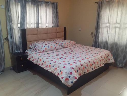 a bedroom with a bed with a floral comforter at GA guest House in Ibadan