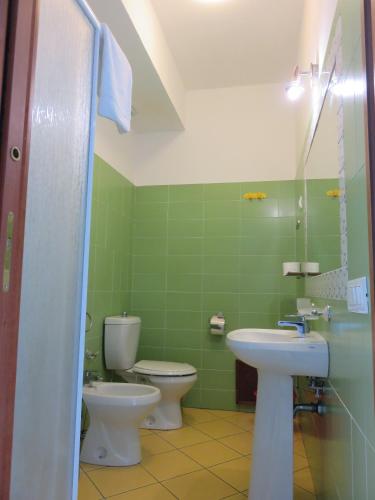 a green bathroom with two toilets and a sink at Case Vacanze Residence Trinacria in Acireale