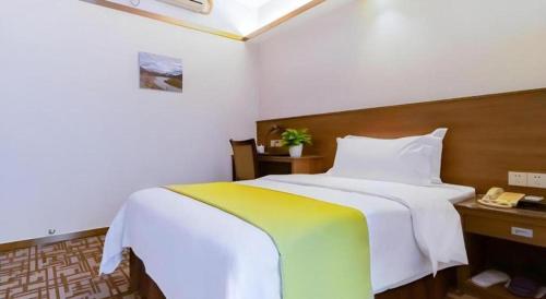 a bedroom with a large white bed and a telephone at My Pleasant Hotel in Shenzhen