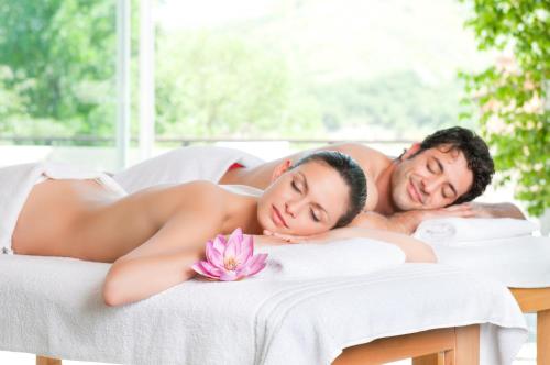 a man and a woman laying on a massage bed with a flower at Terme Villa Pace in Abano Terme