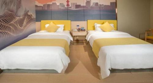 a hotel room with two beds and a painting on the wall at Quanzhou Binhai Hotel in Quanzhou