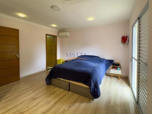 a bedroom with a bed with a blue comforter at Casa Aconchegante na Serra da Cantareira em Condomínio Fechado in Mairiporã