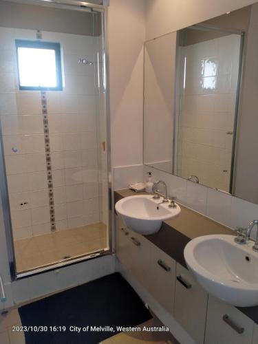 a bathroom with two sinks and a shower at Palmyra Secure holidays Townhouse in Bicton