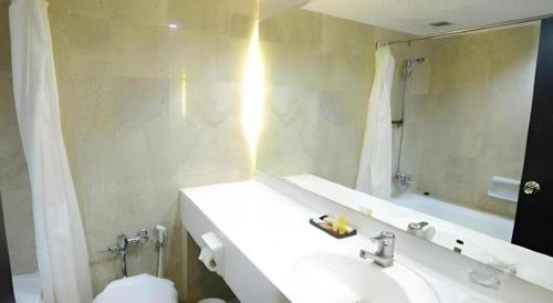 a bathroom with a sink and a toilet and a mirror at Grand Hotel Surabaya in Surabaya