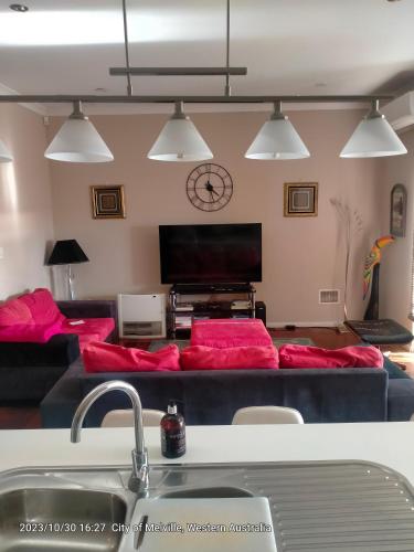 a living room with red couches and a tv at Palmyra Secure holidays Townhouse in Bicton