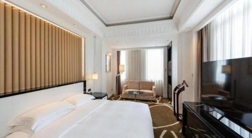 a hotel room with a large bed and a television at Tongxiang Inspirock Hotel in Jiaxing