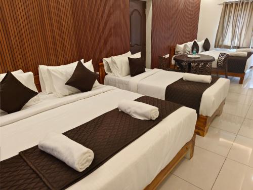 a hotel room with three beds and a table at Sai RBM Grand Inn in Kuilapayam