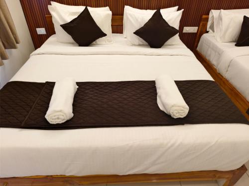 a pair of beds with white sheets and pillows at Sai RBM Grand Inn in Kuilapayam