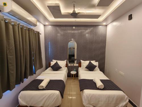 two beds in a room with a mirror at Sai RBM Grand Inn in Kuilapayam