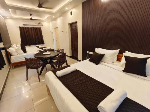 a hotel room with two beds and a table and chairs at Sai RBM Grand Inn in Kuilapayam