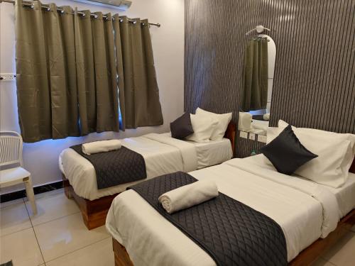 a hotel room with two beds and a mirror at Sai RBM Grand Inn in Kuilapayam