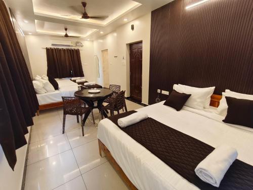 a hotel room with two beds and a table and chairs at Sai RBM Grand Inn in Kuilapayam