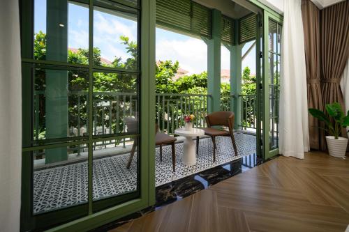 a room with a balcony with a chair and windows at La isla Apartments & Villas - Sea View & Fireworks Phu Quoc in Phu Quoc