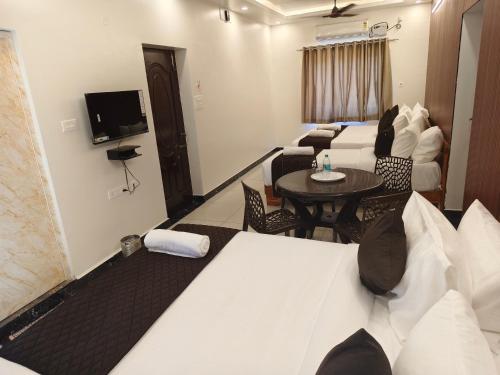 a hotel room with a bed and a table and chairs at Sai RBM Grand Inn in Kuilapayam