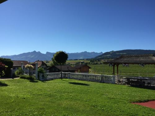 a fence in a field with mountains in the background at Hôtel - Restaurant Le Manoir in Vaulruz